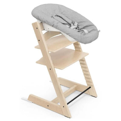 Stokke Tripp Trapp® Newborn chair in natural wood with a gray cushioned seat and safety harness.