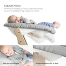Stokke Tripp Trapp® Natural Newborn Set features a baby in a comfortable, adjustable seat with a grey cushion and safety harness.