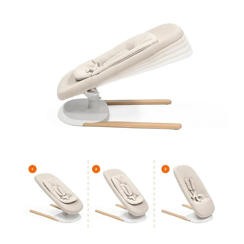 Light sand Stokke Yoga™ Baby Bouncer with three adjustable positions and a modern design, featuring a white base and wooden legs.
