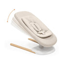 Stokke Yoga™ Baby Bouncer in Light Sand, featuring a soft fabric seat, adjustable reclining position, and wooden base.