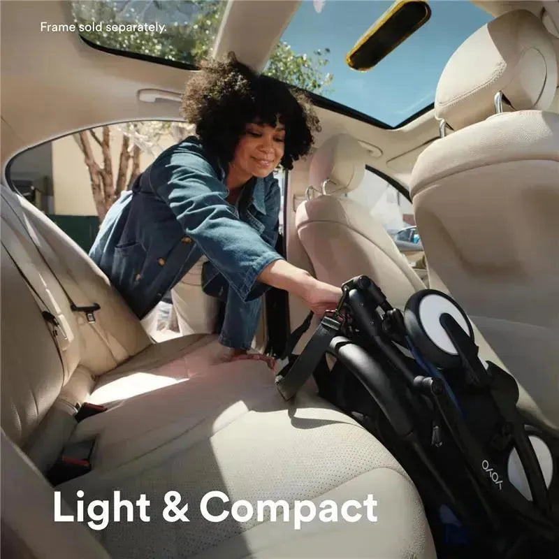A woman fits the Stokke Yoyo 0+ Newborn Pack, Ginger, into the back seat of a car, showcasing its light and compact design.
