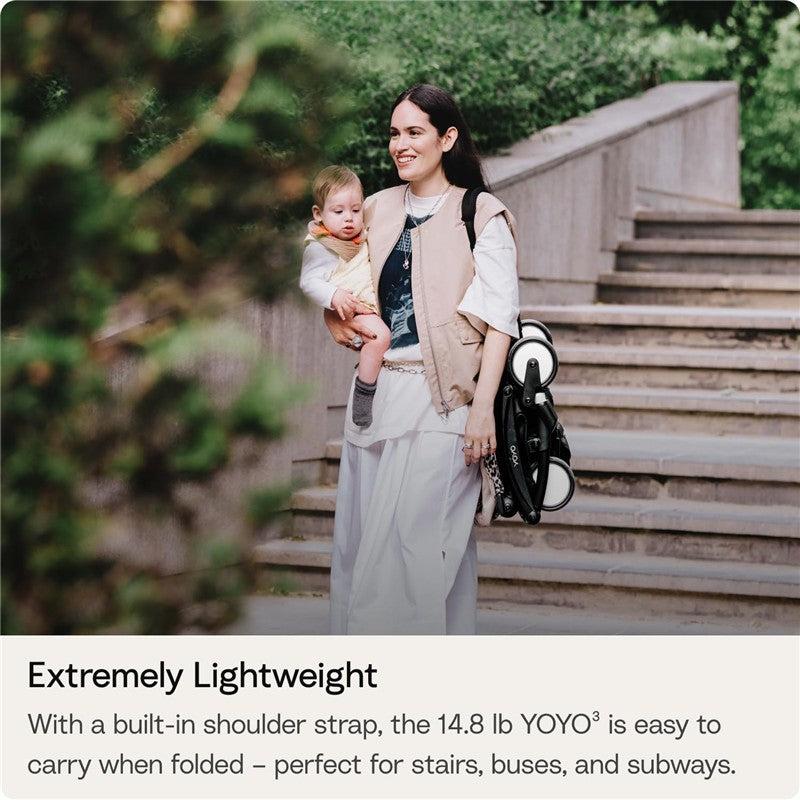 Mother carrying a baby while holding a folded Stokke YOYO3 stroller, showcasing the lightweight and portable design.