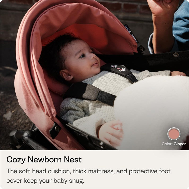 0+ Newborn Pack in Toffee with a baby nestled inside, featuring a soft head cushion and thick mattress for safety.