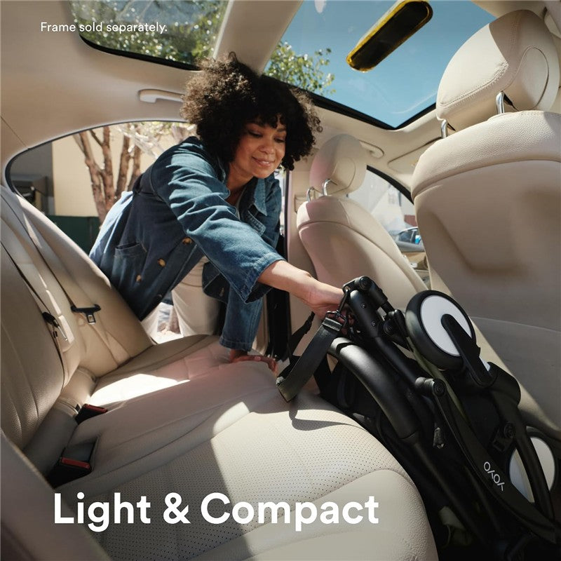 A woman placing a folded Stokke Yoyo 6+ stroller in the backseat of a car, showcasing its light and compact design.