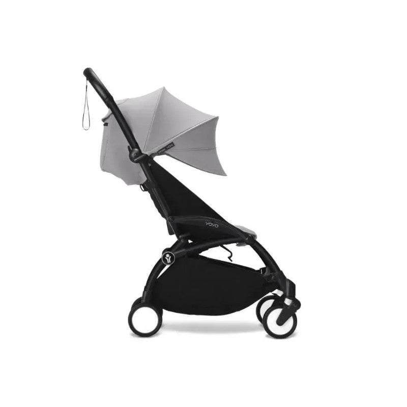 Stokke Yoyo³ stroller with a black frame and stone-colored leg rest, featuring a canopy and compact design.