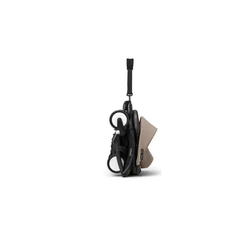 Stokke Yoyo³ stroller in black frame with taupe fabric, shown in a folded position with a carrying strap.