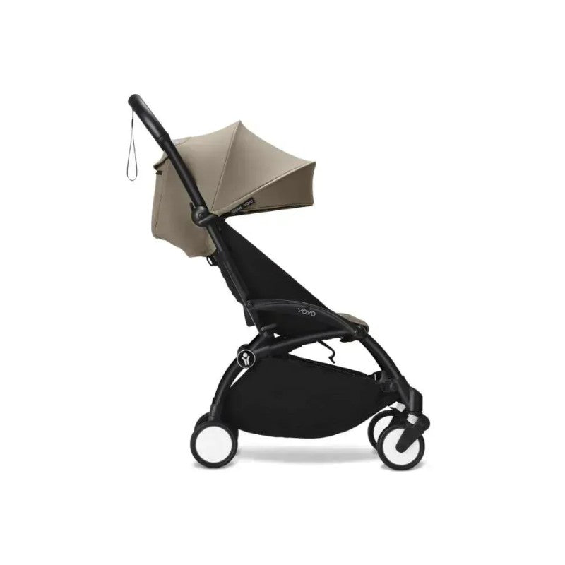 Stokke Yoyo³ stroller with black frame and taupe seat, featuring a canopy and compact design for infants 6+.