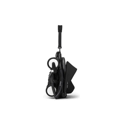 Stokke Yoyo³ stroller in black, folded for easy transport, showcasing its compact design and adjustable carrying strap.