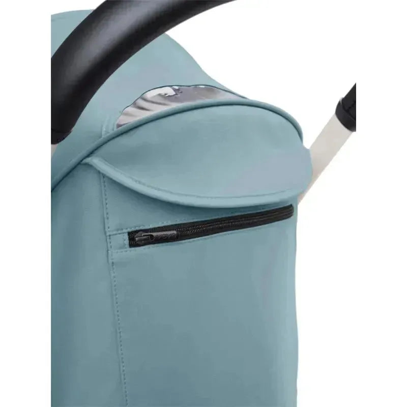 Aqua-colored cover of a Yoyo³ stroller featuring a zippered pocket and part of the handlebars.