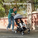 Stokke® YOYO³ stroller frame in black, pushed by a smiling woman, with a happy child inside, outdoors.