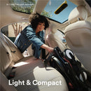 Woman placing a folded black Stokke® YOYO³ stroller in a car, showcasing its light and compact design.
