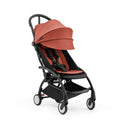 Stokke Yoyo5 compact stroller with a black frame and berry canopy, featuring a comfortable seat and safety harness.