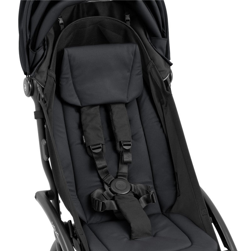 Compact stroller with a black frame and black seating area, featuring a padded seat and safety harness.
