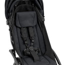 Compact stroller with a black frame and black seating area, featuring a padded seat and safety harness.