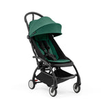 Stokke Yoyo5 compact stroller with a black frame and forest green seat, featuring a canopy and adjustable harness.