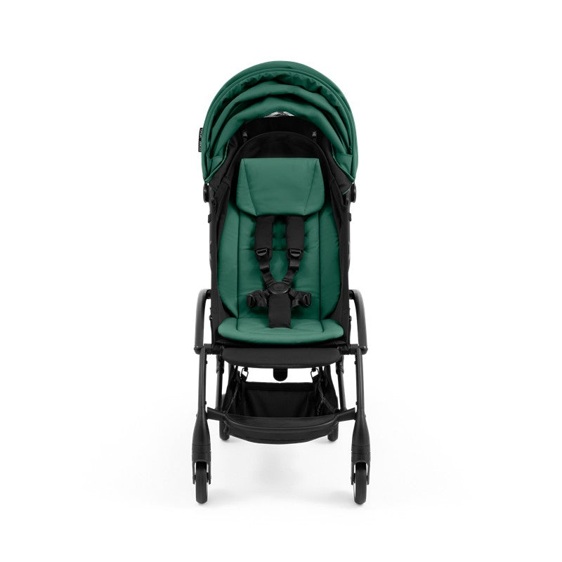 Compact black frame stroller with a green cushioned seat and safety harness, featuring a folding design for easy transport.