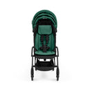 Compact black frame stroller with a green cushioned seat and safety harness, featuring a folding design for easy transport.