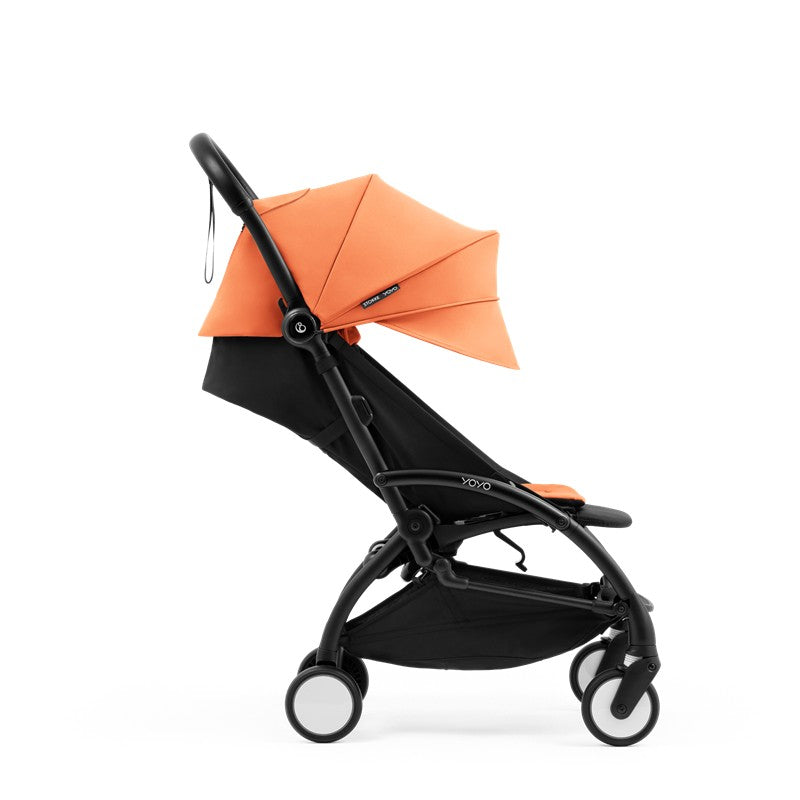 Compact Stokke Yoyo5 stroller with a black frame and peach canopy, showcasing its lightweight and modern design.