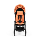Compact Stokke Yoyo5 stroller with a black frame and peach seat, featuring a harness and storage basket.