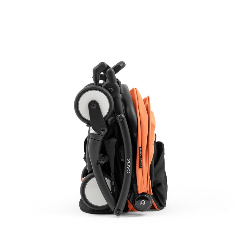 Compact Stokke Yoyo5 stroller in black frame with peach fabric, displayed in a folded position.