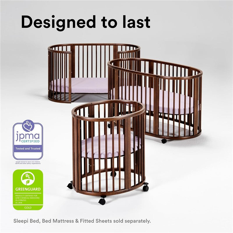 Stokke® Sleepi™ Mini Bundle in Warm Brown features three oval cribs with wooden slats and soft pink mattresses.