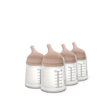 Four Suavinex anti-colic baby bottles with medium-tone lids and measurement markings visible on the sides.
