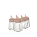 Four Suavinex anti-colic baby bottles with medium-tone lids and measurement markings visible on the sides.