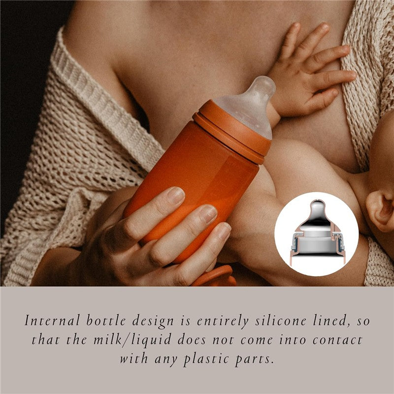 Suavinex Color Essence SX Pro™ Silicone Bottle 8 oz in Irish Cream, being held by a parent with a baby nearby.