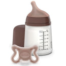 Suavinex Zero Zero Newborn Starter Set featuring a small anti-colic baby bottle and a pacifier, both in neutral colors.