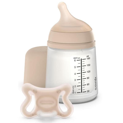 Suavinex Zero Zero Newborn Starter Set featuring a small anti-colic baby bottle and a pacifier, both in light beige.
