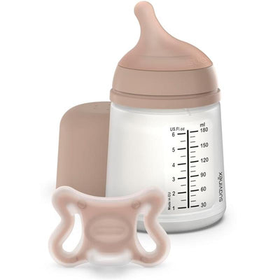 Small anti-colic baby bottle with a beige cap and a pacifier, both from the Suavinex Zero Zero Newborn Starter Set.