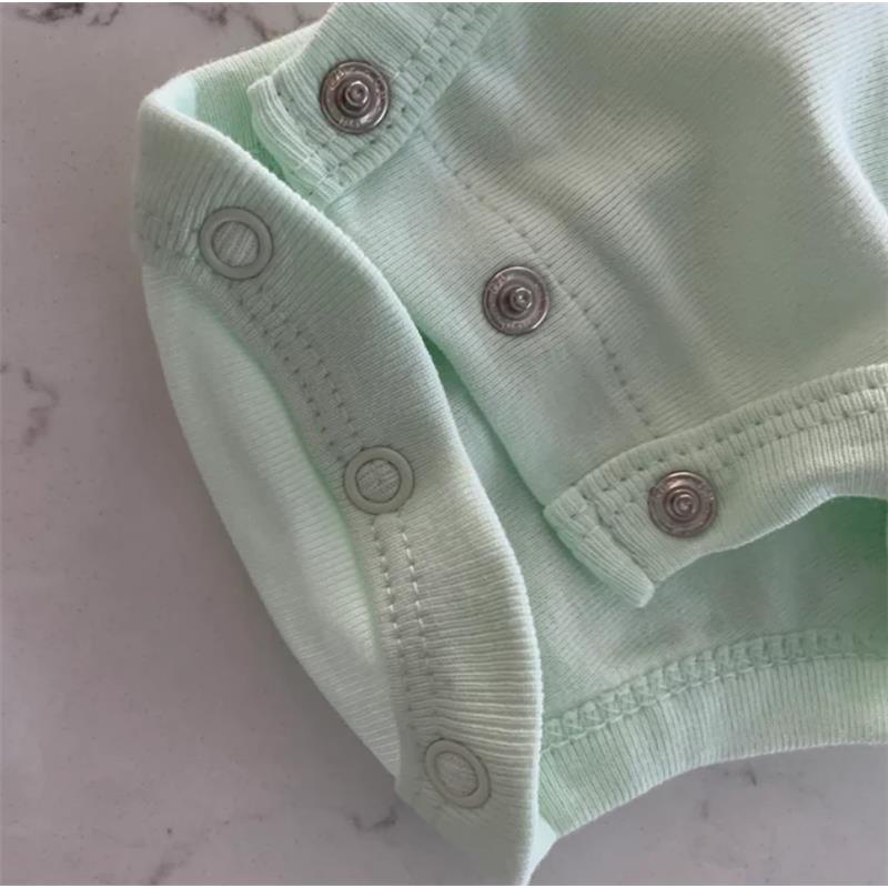 Organic cotton bodysuit in soft jadeite with snap closures, displayed on a light surface.