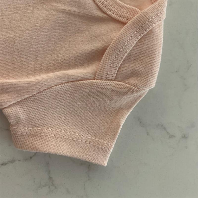 Soft pink organic cotton bodysuit from Swaddle Designs, featuring short sleeves and ribbed neckline, resting on marble surface.