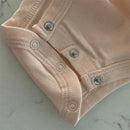 Soft pink organic cotton bodysuit showing snap closures at the bottom, suitable for infants.