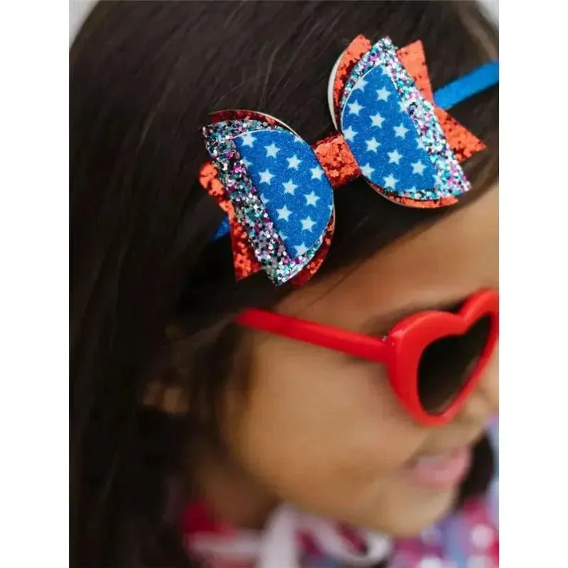 Blue and red 4th of July bow headband with glitter, worn by a girl in heart-shaped sunglasses.