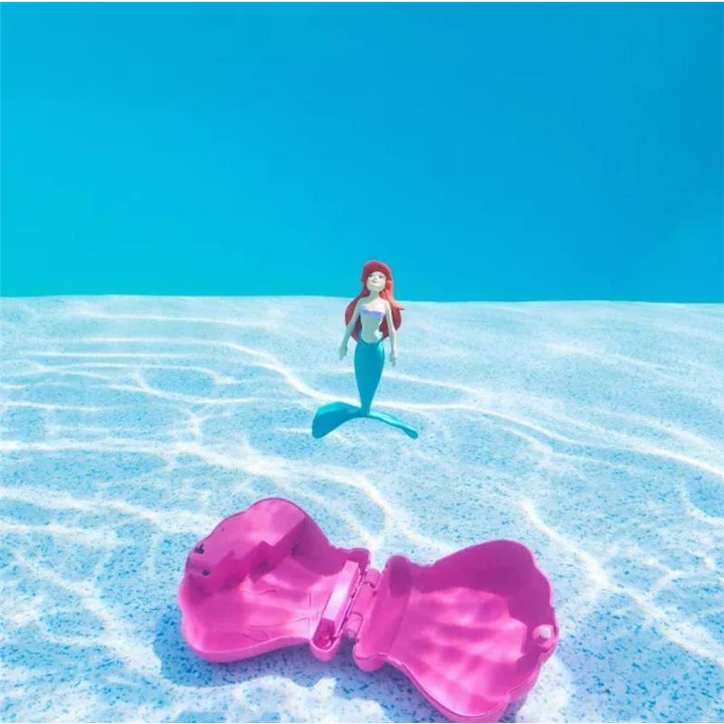 Ariel toy figurine swims in water near an open pink clam-shaped case.