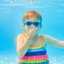 Child wearing Swimways Bluey swim goggles, underwater, holding her nose, in a colorful striped swimsuit.