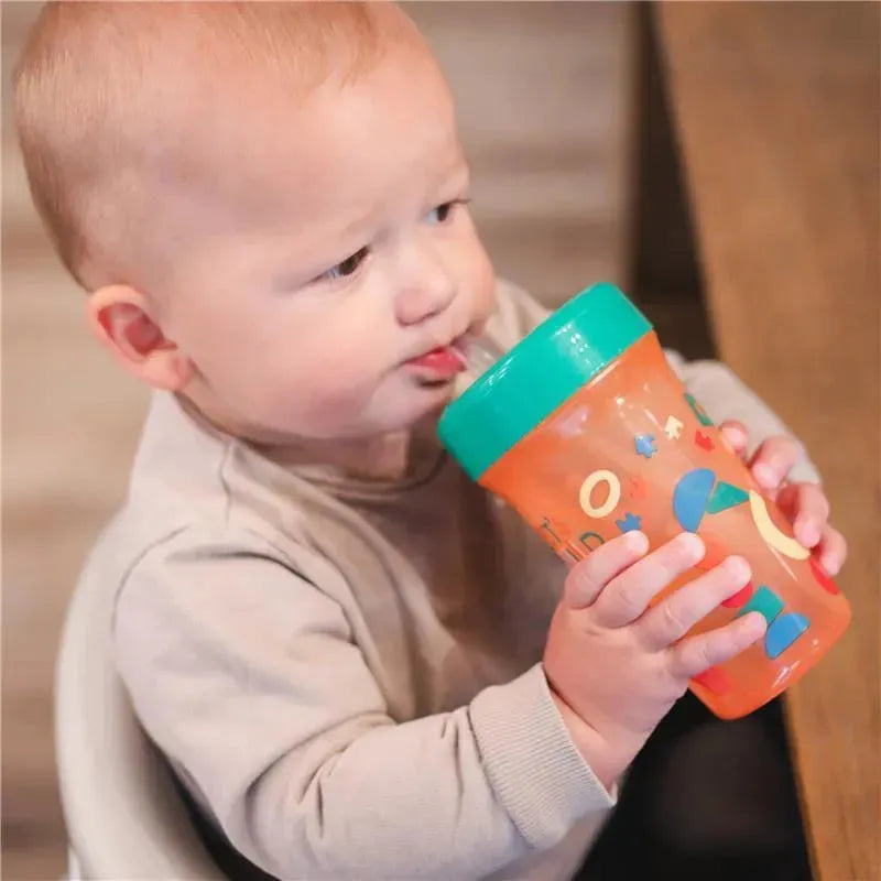 Toddler drinking from The First Years Cocomelon kids straw cup, which is orange with colorful designs and a green lid.