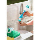 Sponge Mate Baby Bottle Brush in blue, being rinsed under a faucet with dish drying rack in the background.