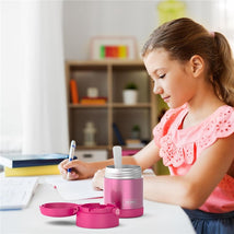 Thermos FUNtainer 10 oz food jar in pink, with a child using a spoon, surrounded by stationery on a desk.