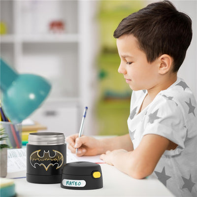 Thermos FUNtainer 10 oz food jar featuring Batman design, with a child writing nearby.