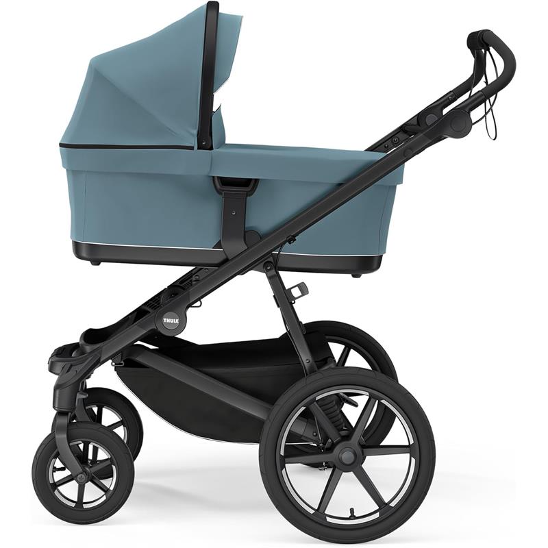 Thule Bassinet Mid in blue, featuring a spacious fabric enclosure on a sturdy stroller frame with large wheels.