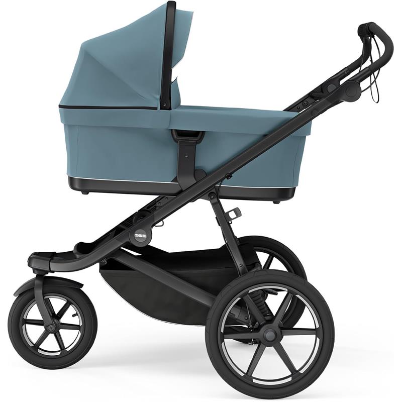 Thule Bassinet Mid in blue, featuring a protective canopy, mounted on a stroller frame with black wheels.
