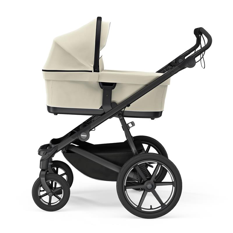 Soft beige Thule bassinet attached to a black stroller frame, highlighting its modern design and spacious interior.