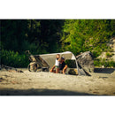 Thule Wind & Sun Tarp used with a Chariot stroller on a sandy area; a parent and child enjoy time together under the tarp.