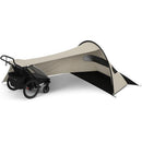 Thule Wind & Sun Tarp set up beside a Chariot Urban Glide stroller, offering shade with a beige and black design.