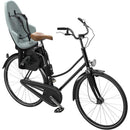 Thule Yepp 2 Maxi child bike seat mounted on a black bicycle, featuring a gray seat and a brown leather seat cover.
