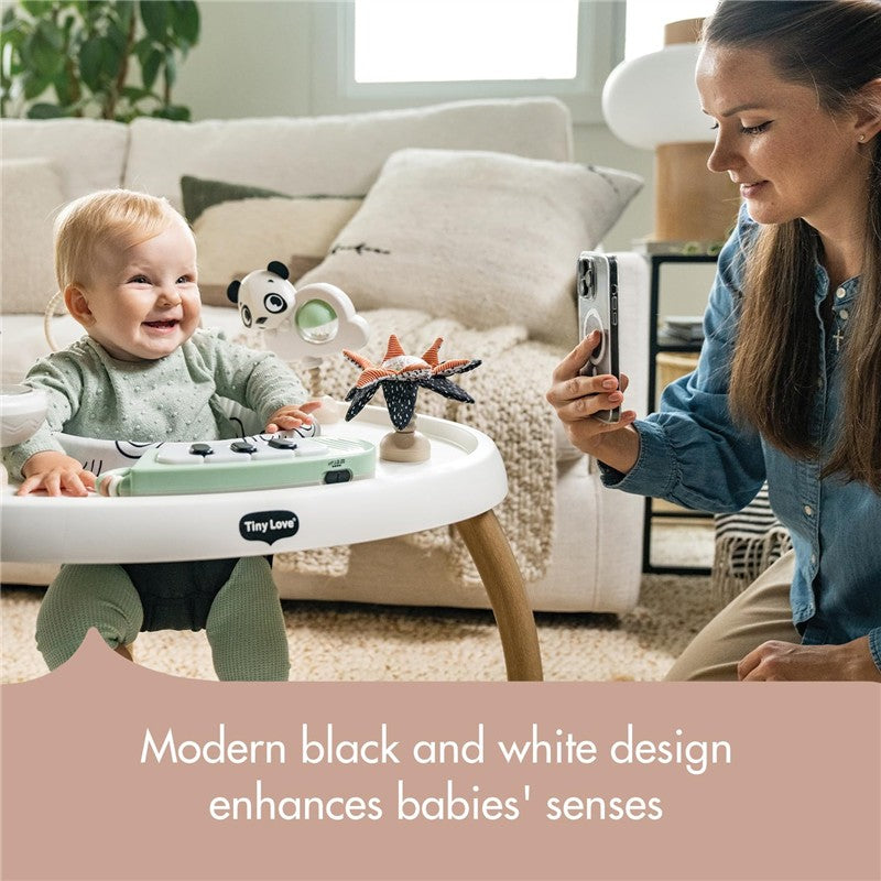 Tiny Love 5-in-1 Here I Grow Activity Center in black and white with a smiling baby and a parent taking a photo.