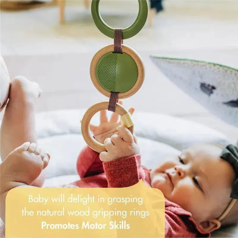 Baby grasps natural wood rings on the Tiny Love Boho Chic Gymini Play Mat, promoting motor skills development.