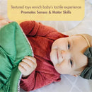 Baby engaged with the Tiny Love Boho Chic Gymini Play Mat, holding a textured toy to enhance sensory development.